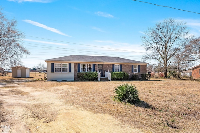 ranch-style home with an outdoor structure, driveway, brick siding, and a shed