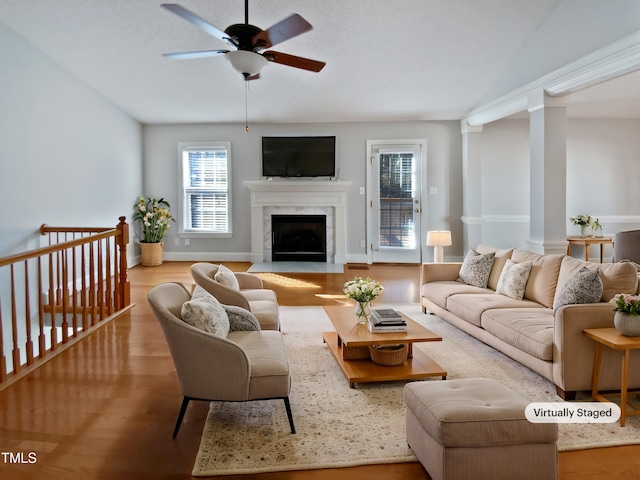 living area with a fireplace, wood finished floors, baseboards, and a ceiling fan