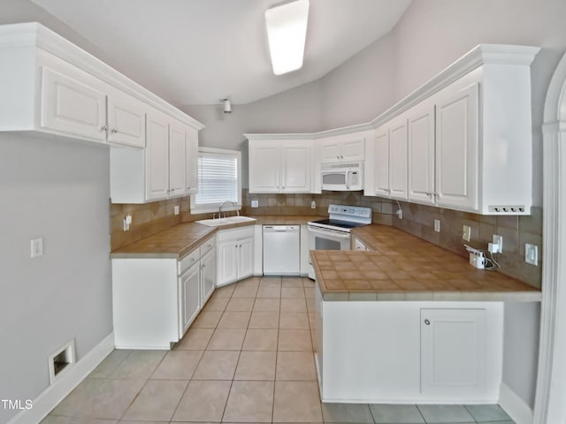 kitchen with a sink, white appliances, white cabinets, and vaulted ceiling