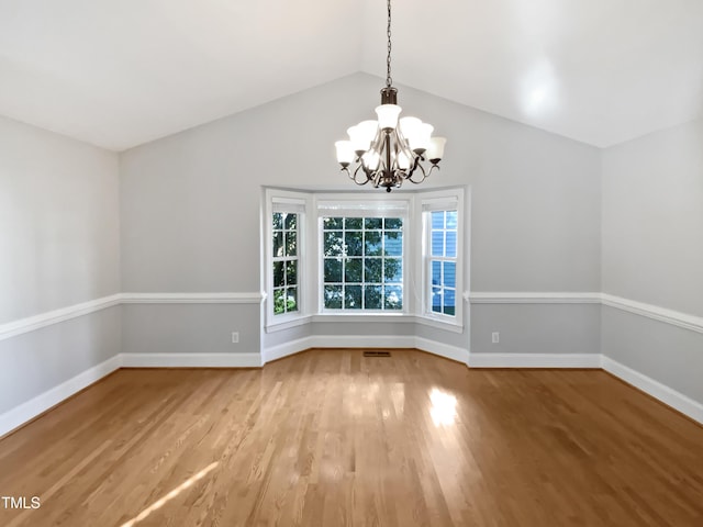 unfurnished dining area featuring visible vents, wood finished floors, baseboards, a chandelier, and vaulted ceiling