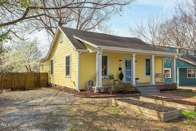 bungalow featuring a shingled roof, fence, a porch, driveway, and a vegetable garden