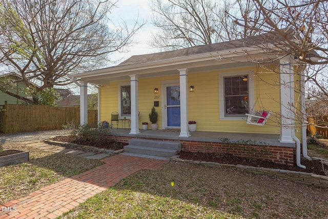 bungalow-style home with a porch and fence