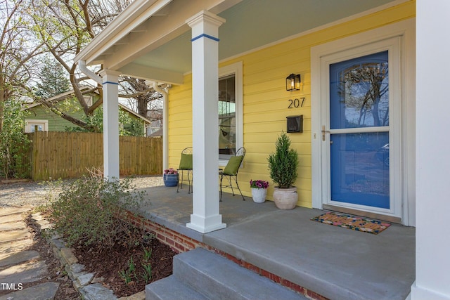 property entrance with a porch and fence