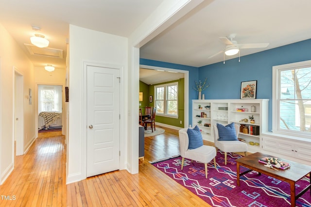 living area with attic access, plenty of natural light, light wood-style floors, and baseboards