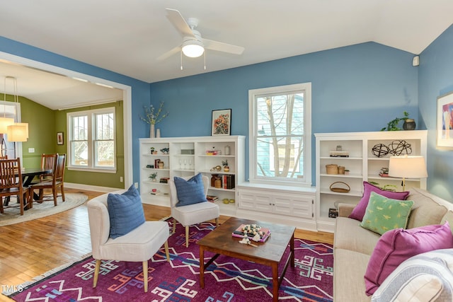 living area featuring baseboards, wood finished floors, a ceiling fan, and vaulted ceiling