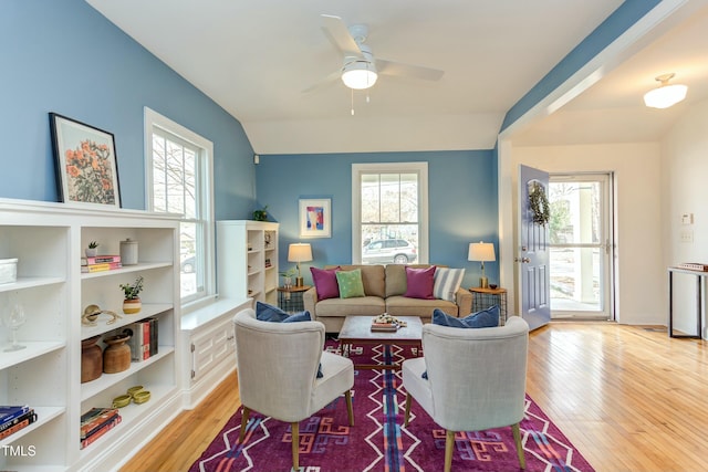 living room with light wood-style flooring, a ceiling fan, a healthy amount of sunlight, and vaulted ceiling