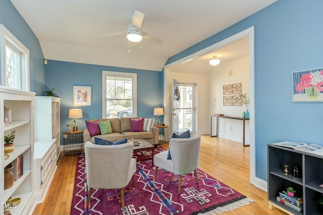 living room with a ceiling fan, vaulted ceiling, wood finished floors, and baseboards