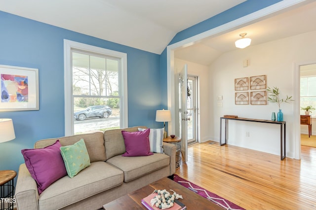 living room featuring baseboards, wood finished floors, and vaulted ceiling