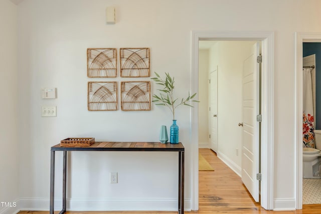 corridor with baseboards and wood finished floors