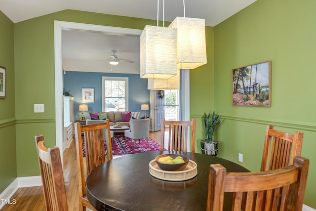 dining area featuring a ceiling fan, vaulted ceiling, wood finished floors, and baseboards