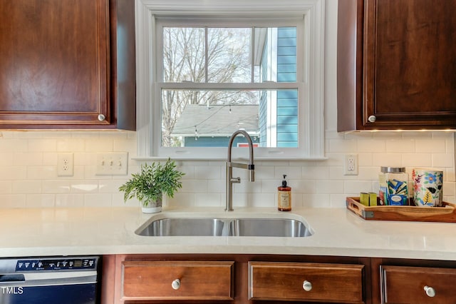 kitchen with decorative backsplash, dishwasher, light countertops, and a sink