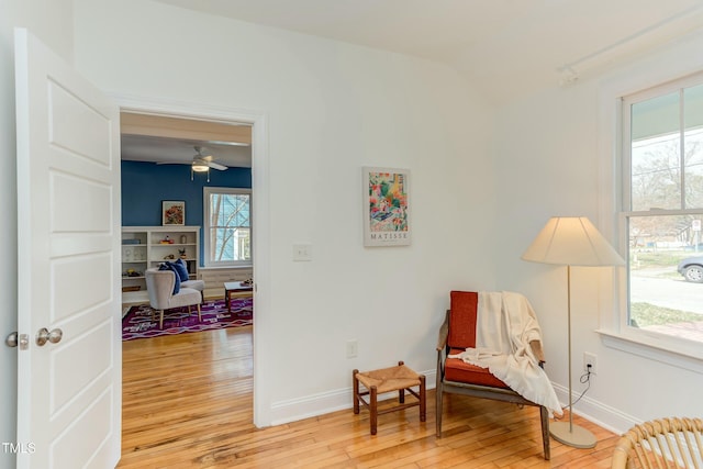 sitting room with baseboards, ceiling fan, and light wood finished floors