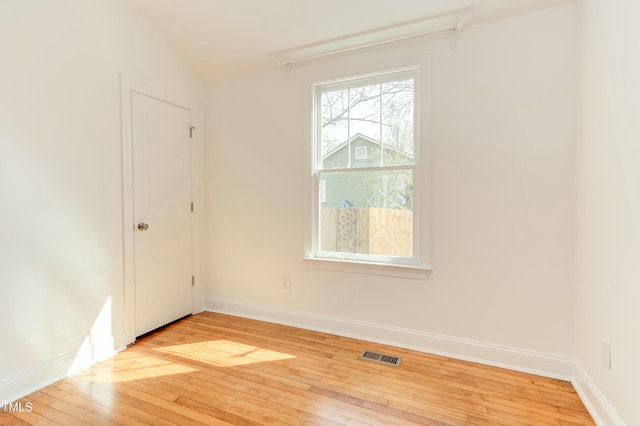 unfurnished room featuring light wood-style floors, visible vents, and baseboards