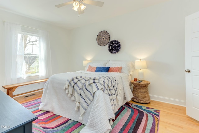 bedroom with visible vents, baseboards, wood finished floors, and a ceiling fan