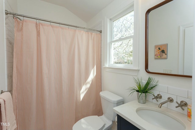 bathroom featuring toilet, vanity, and vaulted ceiling