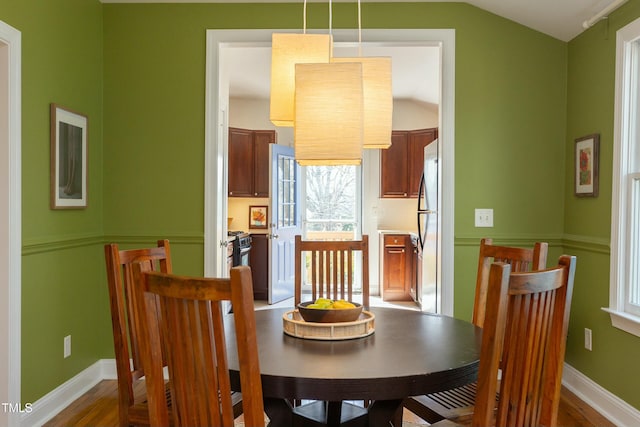 dining area featuring baseboards, lofted ceiling, and wood finished floors