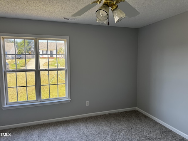 carpeted spare room with visible vents, baseboards, a textured ceiling, and a ceiling fan