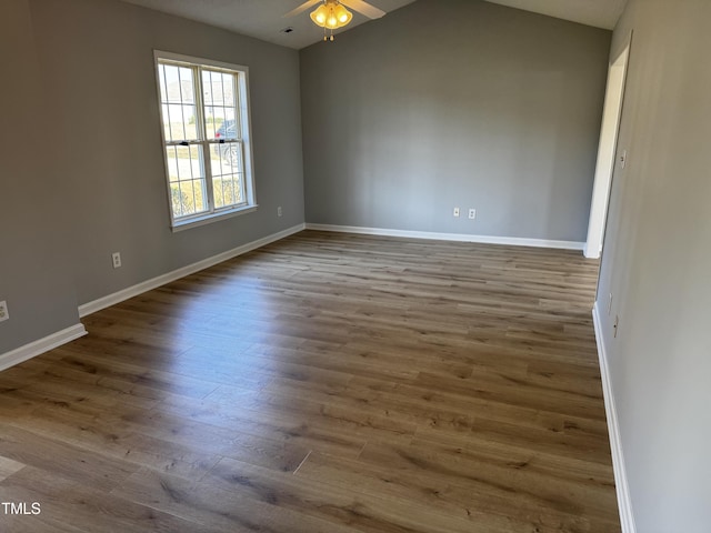 empty room featuring ceiling fan, baseboards, wood finished floors, and vaulted ceiling