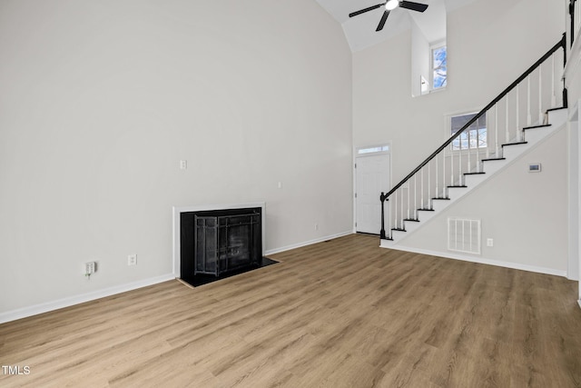 unfurnished living room with visible vents, a fireplace with flush hearth, wood finished floors, and stairs