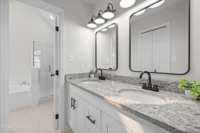 bathroom with double vanity, a stall shower, a garden tub, and a sink