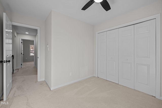 unfurnished bedroom featuring ceiling fan, light colored carpet, a closet, and baseboards