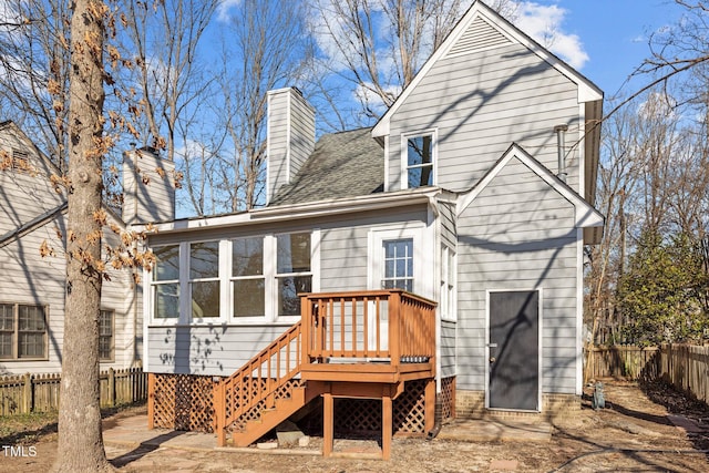 rear view of house with a shingled roof, stairway, a wooden deck, a chimney, and a fenced backyard