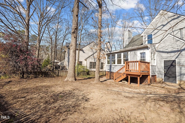 rear view of house with a wooden deck, stairway, a sunroom, and a chimney