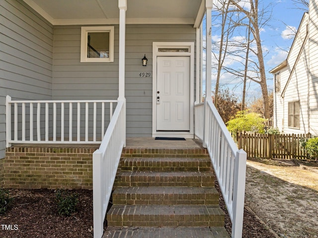 entrance to property featuring a porch and fence