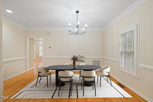 dining space with visible vents, crown molding, baseboards, wood finished floors, and a notable chandelier