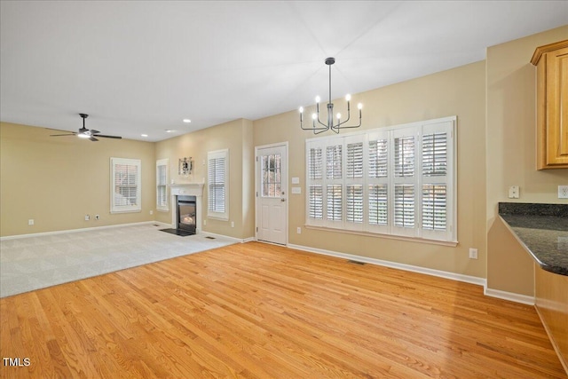 unfurnished living room with a fireplace with flush hearth, a healthy amount of sunlight, light wood-type flooring, and baseboards