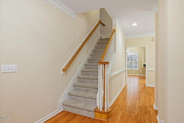 stairway featuring recessed lighting, crown molding, baseboards, and wood finished floors