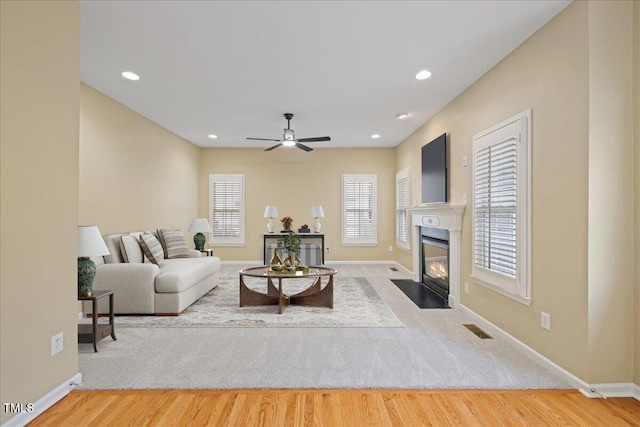 living area with recessed lighting, visible vents, a fireplace with flush hearth, and wood finished floors