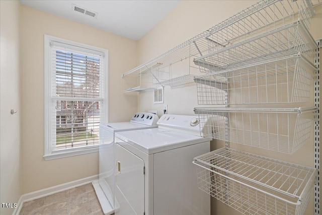 clothes washing area featuring washer and dryer, visible vents, baseboards, and laundry area