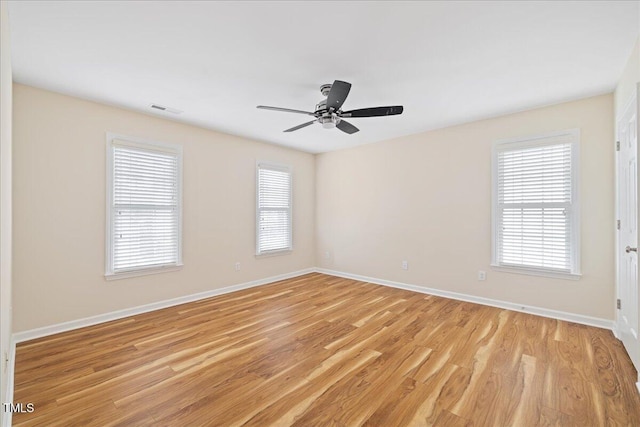 empty room featuring baseboards, visible vents, and light wood-type flooring