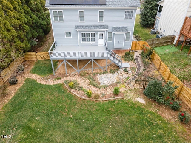 rear view of house featuring a fenced backyard, a lawn, a deck, and roof with shingles