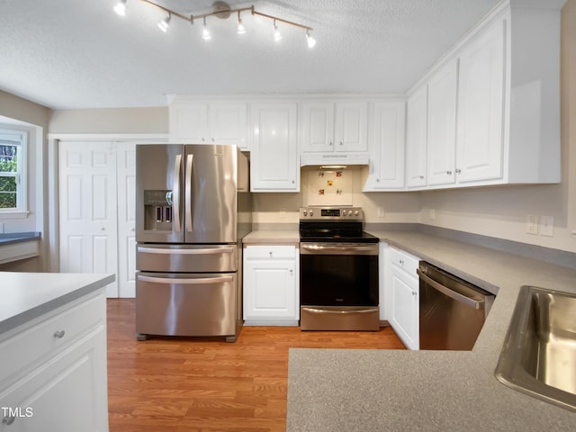 kitchen with under cabinet range hood, white cabinets, and appliances with stainless steel finishes