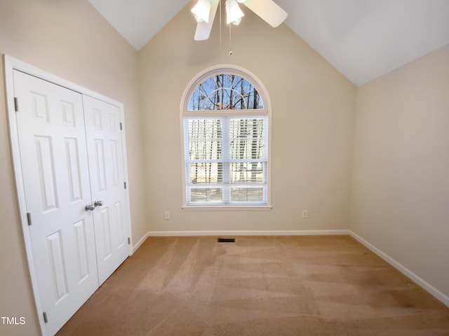 unfurnished bedroom with baseboards, light colored carpet, vaulted ceiling, a closet, and a ceiling fan