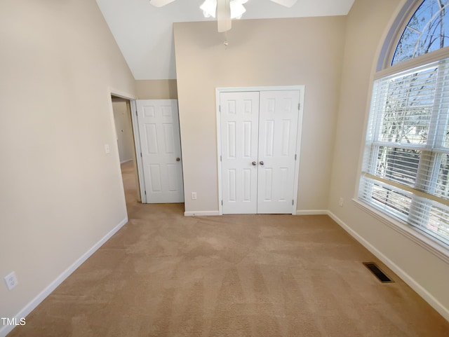 unfurnished bedroom with visible vents, baseboards, light carpet, a closet, and high vaulted ceiling