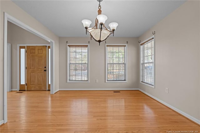 interior space with a chandelier, light wood-style flooring, and baseboards