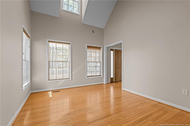 spare room with light wood finished floors, plenty of natural light, visible vents, and baseboards