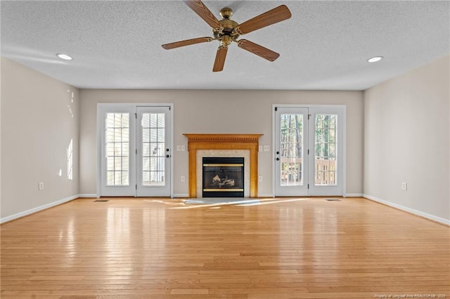 unfurnished living room featuring a premium fireplace, baseboards, and light wood-style floors