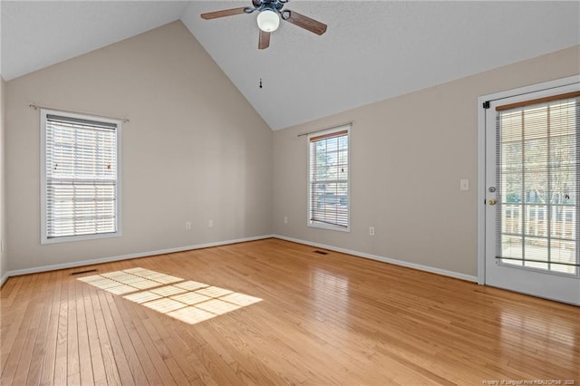 spare room with light wood finished floors, visible vents, baseboards, high vaulted ceiling, and a ceiling fan