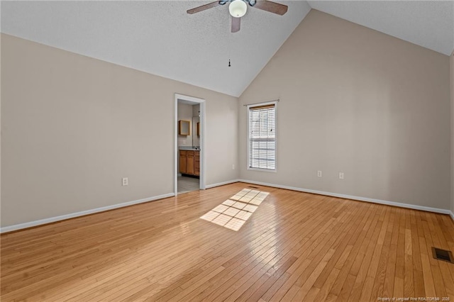 unfurnished bedroom with visible vents, baseboards, high vaulted ceiling, ensuite bath, and light wood-type flooring