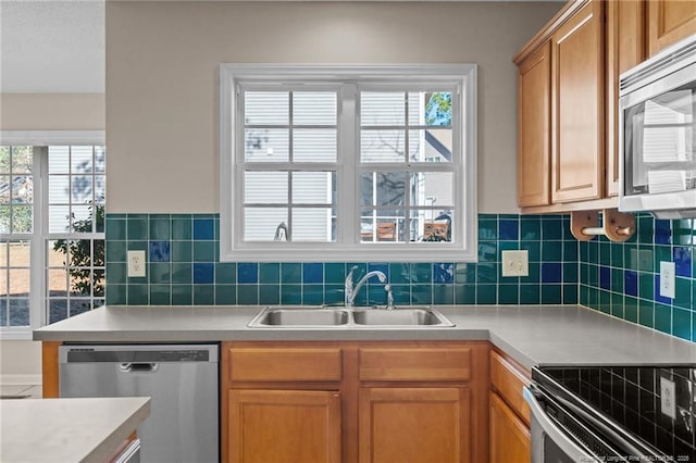 kitchen with a sink, appliances with stainless steel finishes, a wealth of natural light, and light countertops