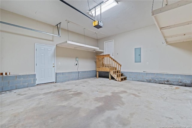 garage featuring electric panel, a garage door opener, and concrete block wall