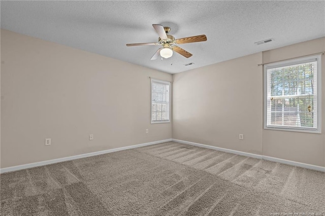 carpeted empty room with visible vents, baseboards, a textured ceiling, and a ceiling fan