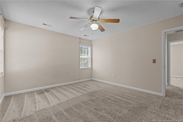 spare room featuring visible vents, baseboards, carpet, and a textured ceiling