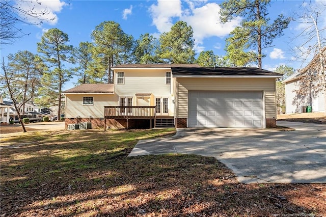 exterior space featuring a deck, concrete driveway, a lawn, and a garage