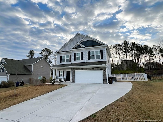 craftsman-style house featuring a garage, covered porch, driveway, and fence