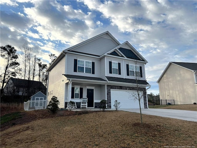 craftsman-style home with an attached garage, concrete driveway, an outdoor structure, stone siding, and a storage shed